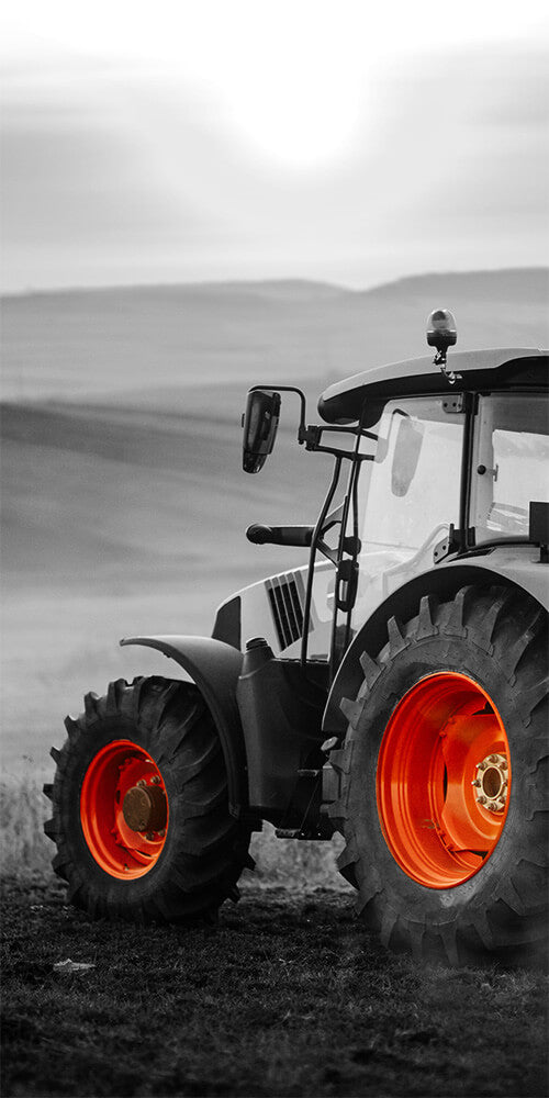 A black and white image of a tractor with vibrant orange wheels.