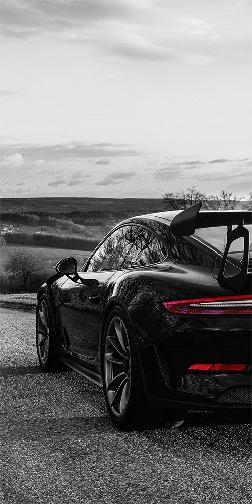 A sleek black sports car with a prominent rear spoiler parked on a quiet road.